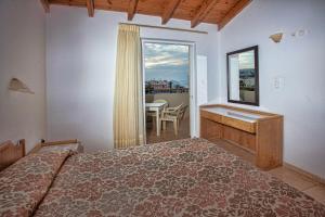 Ilian Beach & Apartments في مدينة ريثيمنو: غرفة نوم بسرير ومكتب ونافذة
