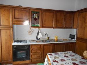 - une cuisine avec des placards en bois, une cuisinière et un évier dans l'établissement mansarda La Ruine, à Morgex