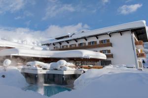 a hotel covered in snow with a swimming pool at Gut Wenghof - Family Resort Werfenweng in Werfenweng