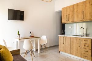 una cocina con armarios de madera y sillas blancas en Castell Hotel en Kissamos