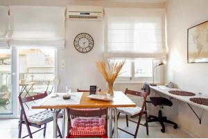 a dining room with a table and chairs and a clock at Stylish Boutique Condo in Heraklio Town