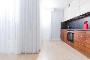 kuchnia z białymi zasłonami i drewnianymi szafkami w obiekcie Resort Apartamenty Klifowa Rewal 14 w Rewalu
