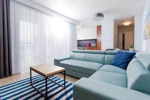 ein Wohnzimmer mit einem blauen Sofa und einem Tisch in der Unterkunft Resort Apartamenty Klifowa Rewal 14 in Rewal