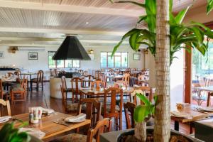 a restaurant with wooden tables and chairs and a plant at Houw Hoek Hotel in Botrivier
