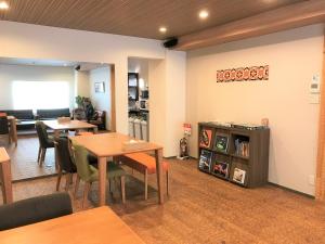 K's House Kanazawa - Travelers Hostel في كانازاوا: غرفة طعام مع طاولات وكراسي وغرفة معيشة