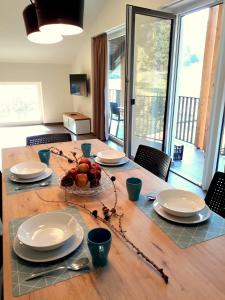 a wooden table with plates and bowls of fruit on it at Apartments ALPA VITA in Kobarid