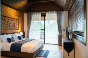 a bedroom with a large bed and a television at Phor Liang Meun Terracotta Arts in Chiang Mai