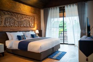 a bedroom with a large bed and a large window at Phor Liang Meun Terracotta Arts in Chiang Mai