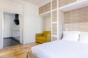 a bedroom with a white bed and a yellow chair at São Francisco in Matosinhos