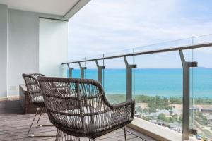 une chaise en rotin assise sur un balcon donnant sur l'océan dans l'établissement Elnob Seaview Aparthotel Hai Tang Bay Sanya, à Sanya
