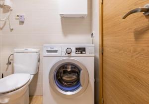 une petite salle de bains avec un lave-linge et des toilettes. dans l'établissement Stellamar - Paseo Maritimo, à Fuengirola