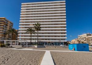 een groot wit gebouw aan het strand met palmbomen bij Stellamar - Paseo Maritimo in Fuengirola