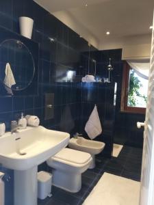 a blue tiled bathroom with a sink and a toilet at Villa Barbara in Giardini Naxos
