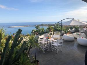 a patio with white chairs and tables and the ocean at Villa Barbara in Giardini Naxos