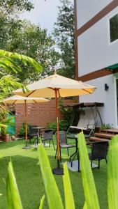 un patio con tavoli, sedie e ombrellone di Top Hostel Samui a Chaweng Beach