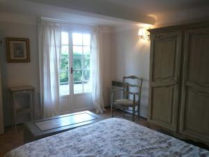 a bedroom with a bed and a chair and a window at Maison Le Retour in Le Rouret