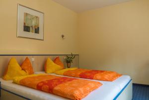 two beds with orange and yellow pillows in a room at Hotel Papillon in Lappersdorf