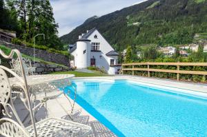 a swimming pool with chairs and a house and mountains at Villa Behrens in Bad Gastein