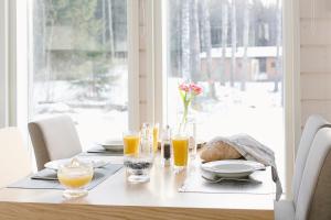 a table with glasses of orange juice and bread on it at WOODDREAM in Taipalsaari