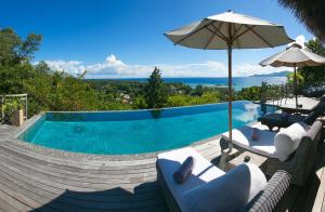 einen Pool mit 2 Stühlen und einem Sonnenschirm in der Unterkunft Le Domaine de L'Orangeraie Resort and Spa in La Digue