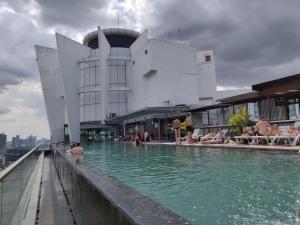 a pool in front of a building with people in the water at StarsBed KLCC Skyview Roof Pool Hostel in Kuala Lumpur
