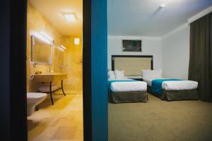 a bedroom with two beds and a bathroom with a sink at Primera Dru Hotel&Spa in Baia Mare