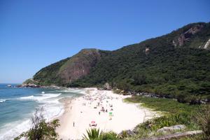 a group of people on a beach near the ocean at Casa em Condomínio in Rio de Janeiro