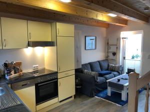 a kitchen and living room with yellow cabinets and a couch at Ein kleines Haus in Fehmarn