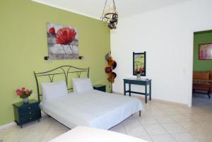 ミティムナにあるMolyvos Queen Apartmentsの緑の壁のベッドルーム1室(白いベッド1台付)
