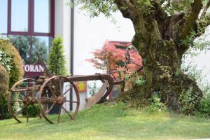 a rusty cart sitting next to a tree at Hotel Da Franco in Nogarole Rocca