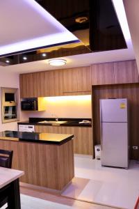 a kitchen with a white refrigerator and wooden cabinets at The 21 MuangthongThani in Pak Kret