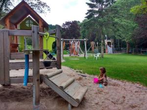 une petite fille assise dans le sable sur une aire de jeux dans l'établissement Ferienwohnung Rhododendron - Natur pur am Highwalk, à Rotenburg an der Fulda