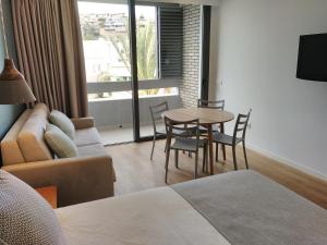 sala de estar con sofá, mesa y sillas en Apartamentos Ciudad Jardín, en Las Palmas de Gran Canaria