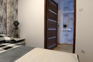 a bedroom with a bed and a wooden door at Apartament Columbus in Ustrzyki Dolne