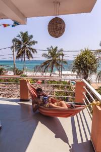 a man laying in a hammock on the beach at Coppenrath Hostel in Tangalle