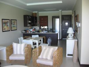 a living room with chairs and a table and a kitchen at Eden Island luxury apartment sea view in Eden Island