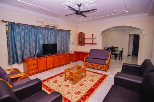 a living room with a tv and chairs and a table at Vintage Homestay in Perai