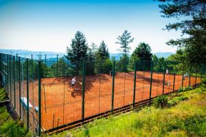 a fence with people riding horses on a tennis court at Hotel Monínec - Depandance Nová Javorka in Moninec