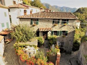 uma velha casa de pedra com flores em frente em B&B La Margine e SPA em Cocciglia