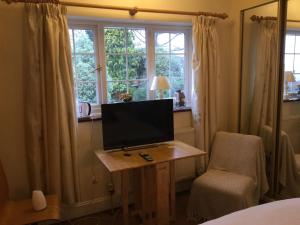 TV en una mesa en una habitación con ventanas en Maggi’s Home from Home en Sheffield