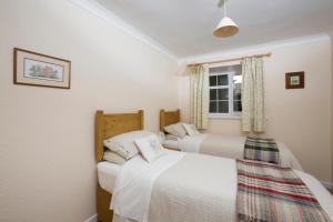 2 łóżka w małej sypialni z oknem w obiekcie Stable Cottage w mieście Bardon Mill