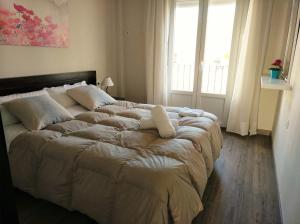 ein großes Bett in einem Schlafzimmer mit einem großen Fenster in der Unterkunft Apartamento Plaza Compañia Jerez in Jerez de la Frontera