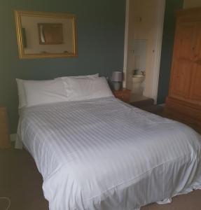 a large white bed in a bedroom with a bathroom at Queensberry Arms Hotel in Annan