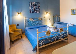a bedroom with two blue beds and a chair at SCIUSCIA' in Alcamo Marina
