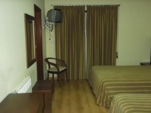 a hotel room with two beds and a chair at Hotel Minho Belo in Vila Nova de Cerveira