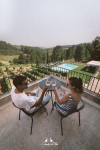 un uomo e una donna seduti a un tavolo con bicchieri da vino di Quinta de Fiães a Vilar de Maçada