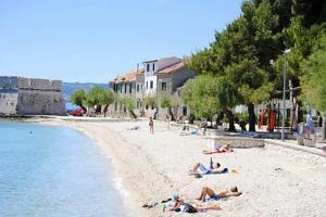 um grupo de pessoas deitadas numa praia junto à água em Seaview Pool Villa with cinema up to 26 em Kaštela