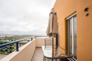 a balcony with an umbrella and a table and chairs at Elegant Sea View Apartment in Nazaré