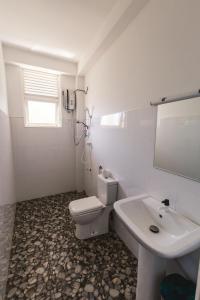 a white bathroom with a toilet and a sink at Coppenrath Hostel in Tangalle