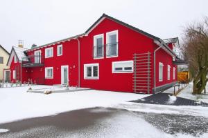 a red house with snow on the ground at Ferienwohnung Lausitzer Seenland Tom in Großräschen